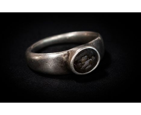 Roman (2nd-4th century AD) Silver ring with plain flat band; oval bezel set with a glass intaglio engraved with a set of scal