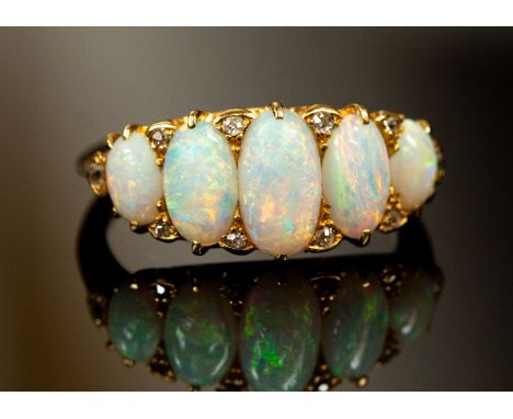 An Edwardian diamond and opal set ring, comprising five graduated oval cabochon opals, the largest central opal measuring app