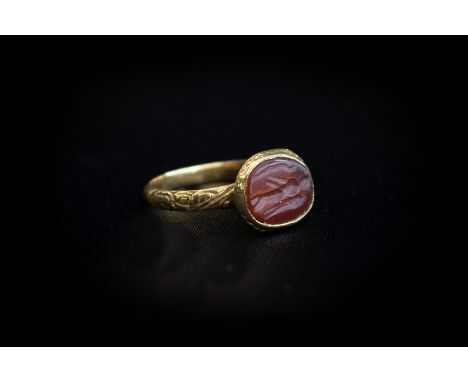 Roman (1st-3rd century AD) A gold ring with decorated band; oval bezel set with carnelian intaglio engraved with the standing