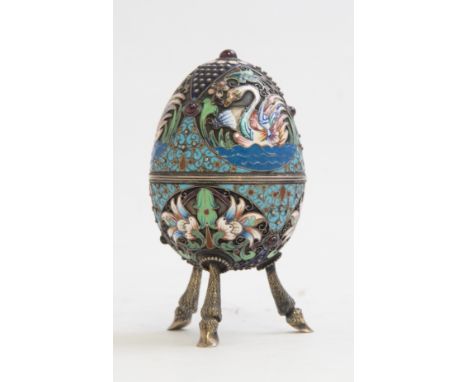 A Russian silver gilt and cloisonné enamelled egg, on three cast hoof legs, three champleve enamel swans, below foliate carto