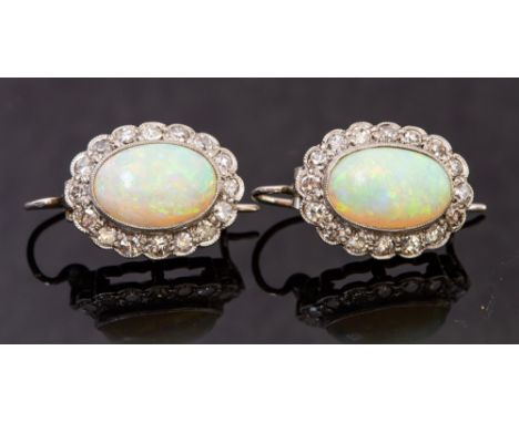 A pair of white metal, opal and diamond earrings, the oval cabachon opal approx 11mm x 8mm, each surrounded by sixteen round 