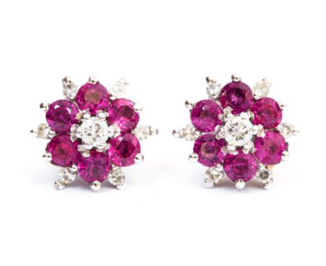 A pair of flower head ruby and diamond cluster earrings, each set with six, 2.7mm round cut rubies, with diamond accents and 