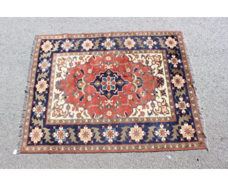 A Persian carpet, of Turkish style having geometric floral patterns on a red ground with a deep blue ground border, 200cm x 1