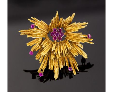 An 18ct yellow gold stylised star burst ruby set brooch, central flower head cluster and border comprising total of twelve sm
