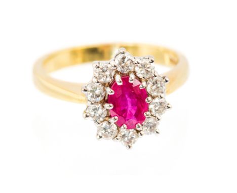 An 18ct yellow gold, ruby and diamond cluster ring, the central oval cut ruby approx 7.3mm x 5.3mm, surrounded by ten round b