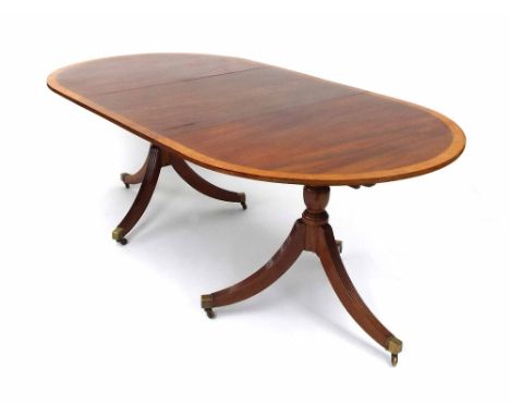 Georgian style mahogany twin pedestal extending dining table, with a maple crossbanded top upon turned columns and reeded tri