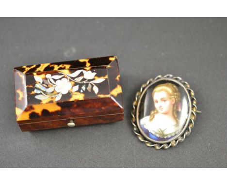 A Victorian tortoiseshell pillbox decorated with mother of pearl, together with an oval white metal brooch mounted with a pai