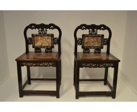 A pair of Chinese hardwood side chairs, carved foliate decoration to back, inset rouge marble panels to seats and backs, moth