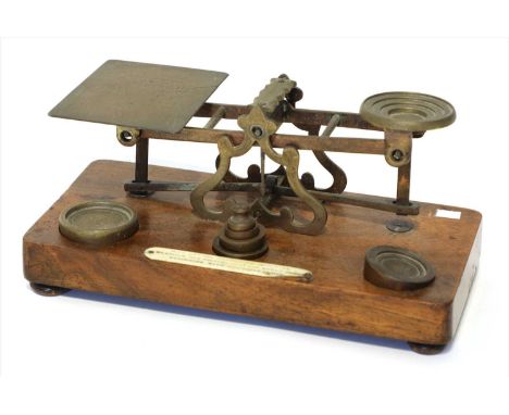 A set of brass postal scales, by Sampson Mordan &amp; Co., late 19th century, the walnut base supporting six weights from ¼oz