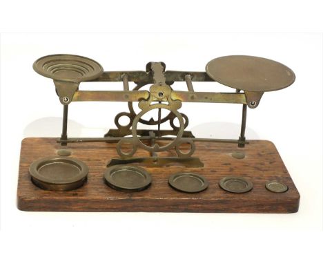 A large set of brass postal scales, by Edmund Ratcliff, c.1864/71, the oak base supporting five cased weights from ½oz to 8oz