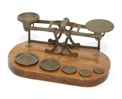 A set of brass postal scales, by J &amp; E Ratcliff, late 19th century, the lozenge form oak base supporting five weights fro
