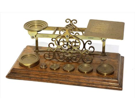 A set of brass postal scales, by Sampson Mordan &amp; Co., late 19th to early 20th century, the oak base supporting six weigh