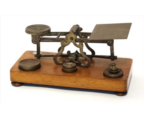 A set of brass postal scales, by Sampson Mordan &amp; Co., late 19th century, the oak base supporting six weights from ¼oz to
