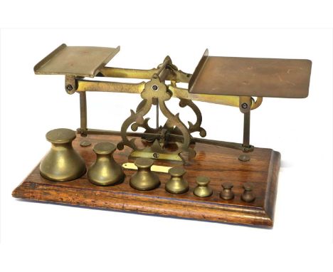 A large set of brass postal scales, in the manner of J &amp; E Ratcliff, late 19th century, with seven bottle-shaped weights,