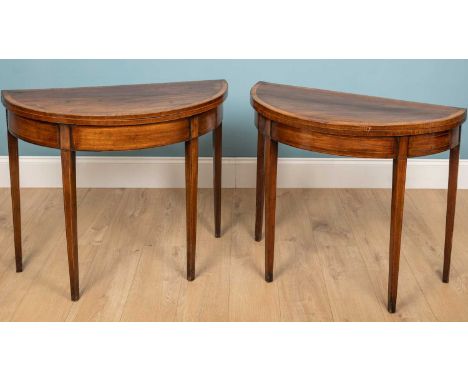 A near pair George III demi-lune card tables, mahogany with fold over tops, a crossbanded border and square tapered legs. Wit