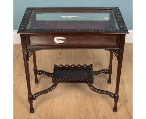 An Edwardian bijouterie table, mahogany with glass lid and intricately carved detail on the wooden lid surface and carved det