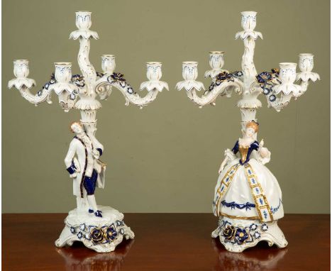 A pair of four-branch German porcelain candelabra, modelled as a gallant and female companion in blue and gilt, each inscribe