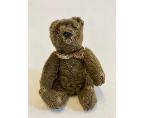 Small Steiff jointed bear, with glass eyes, brown plush, fabric bow and white metal ear button, 5 1/2" longCondition Report: 