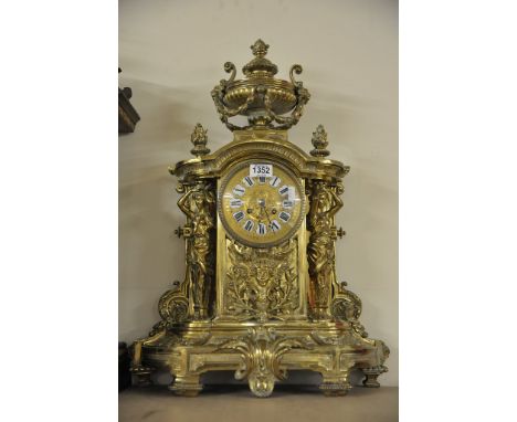 A large and impressive 19th century brass clock surmounted by an urn finial, the dial flanked by supportive maidens