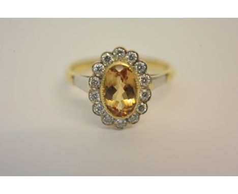 A ladies 18ct gold ring set with a central oval cut orange-brown stone (possibly imperial topaz) with diamond surround