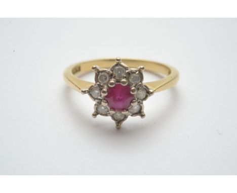 A ladies 18ct gold ring set with a central round cut ruby with diamond surround