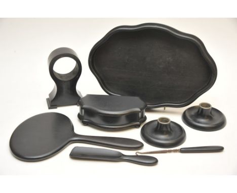 A collection of ebony dressing table items comprising tray, clock housing, hand mirror, a pair of black plastic candlesticks 