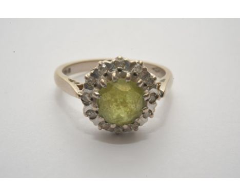 A ladies 18ct white gold ring set with central round cut peridot with diamond surround