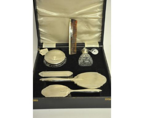 A quality cased silver dressing table set of Art Deco design comprising two silver backed brushes, a silver backed mirror, a 