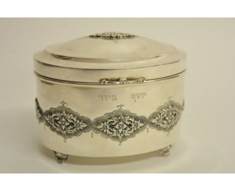 An oval sterling silver tea caddy with raised foliate decoration and gilt interior