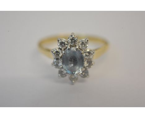 A ladies 18ct yellow gold ring set with central oval cut aquamarine with diamond surround