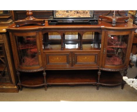 An Edwardian inlaid mahogany chiffonier base fitted with central open shelf flanked by bow fronted glazed doors