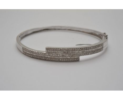 A ladies 18ct white gold bangle profusely set with round and baguette cut diamonds