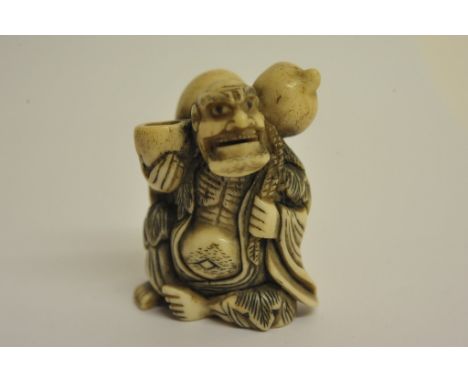 A Japanese stag antler netsuke in the form of a robed elder with a double gourd upon his back
