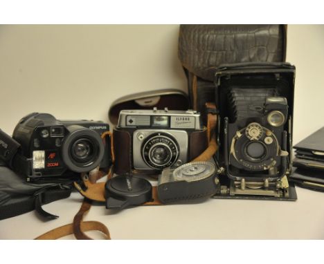 A collection of three cameras comprising a Kompur plate camera, an Olympus and an Ilford Sportman