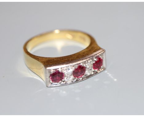 A modern 18ct yellow metal, three stone ruby and four stone diamond half hoop ring, size O, gross weight 7.4 grams.CONDITION: