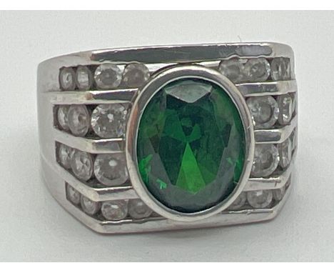 A modern Art Deco design silver cocktail ring. Set with an oval cut central green stone with 4 rows of channel set clear ston