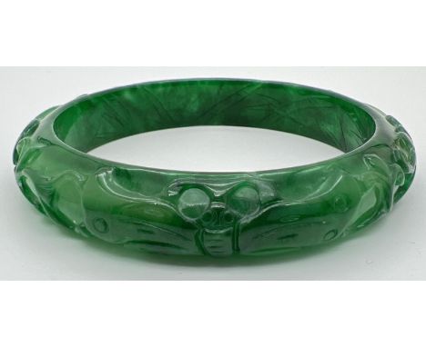A Chinese green jade bangle with carved flower &amp; butterfly design. Approx. 7.5cm diameter. 