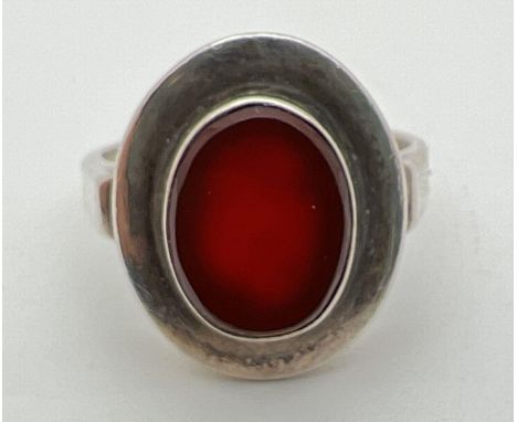 A silver contemporary style oval shaped ring set with carnelian. 925 stamped to inside of band. Size T. 