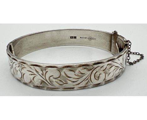 A vintage silver bangle with full floral engraved decoration and safety chain. Hallmarked Birmingham 1974. Total weight appro