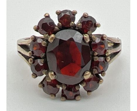 A vintage silver cocktail style ring set with Garnets. oval cut central garnet surrounded by 10 small round cut garnets. Silv