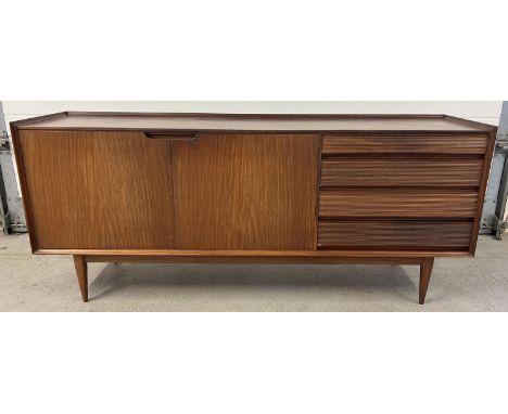 A mid century Afrormosia wood triple sideboard by Richard Hornby for Heals. Raised on tapered legs, with 4 drawers to include