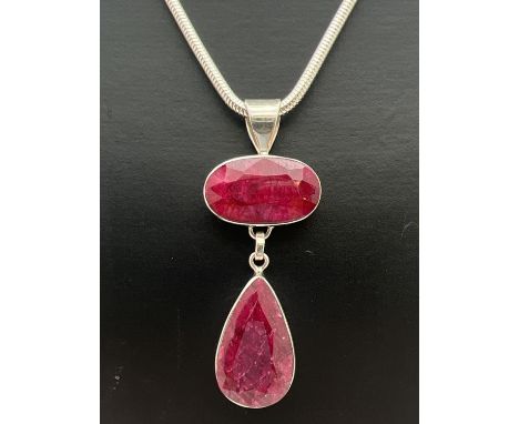 A modern design drop style silver pendant set with an oval cut and a teardrop cut ruby. On a 16 inch snake chain with lobster