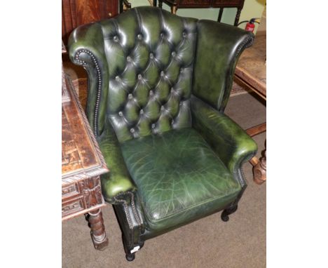 A Georgian style buttoned green leather wing back armchair 