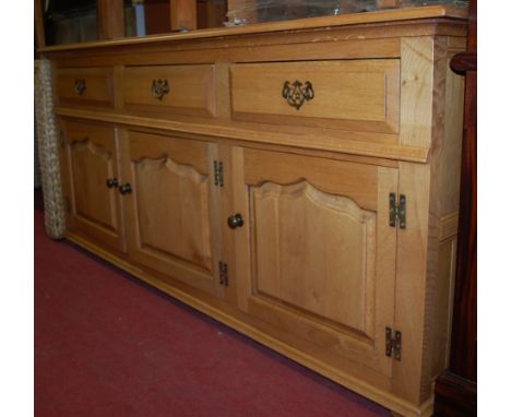 A contemporary joined light oak sideboard in the 18th century style, having three frieze drawers above three recessed panelle
