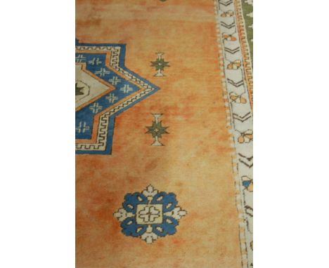 A Caucasian woollen peach ground carpet having twin medallions within trailing borders, 290x213cm