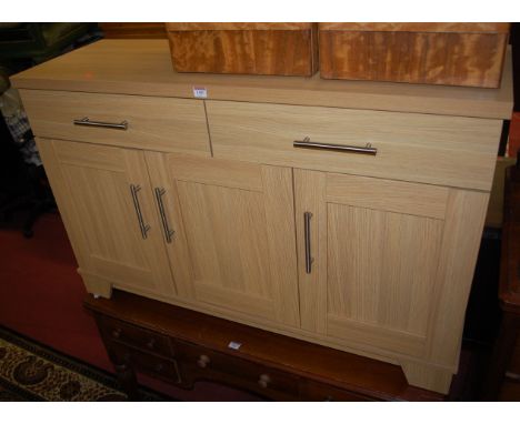 A contemporary light oak effect three door sideboard, having twin upper drawers