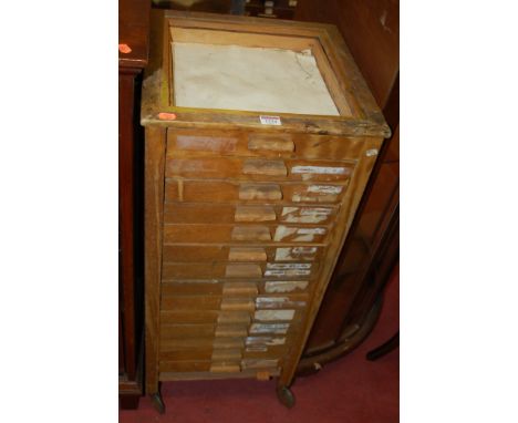 An early 20th century light oak 14-drawer narrow collectors chest, on roller casters (lacking top surface), w.39cm