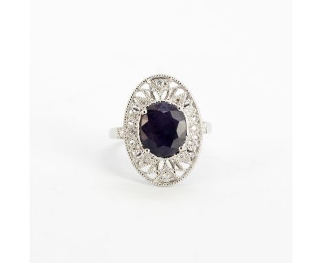 An 18ct white gold ring set with a large oval cut purple sapphire, approx. 3.45ct, surrounded by diamonds, (M).