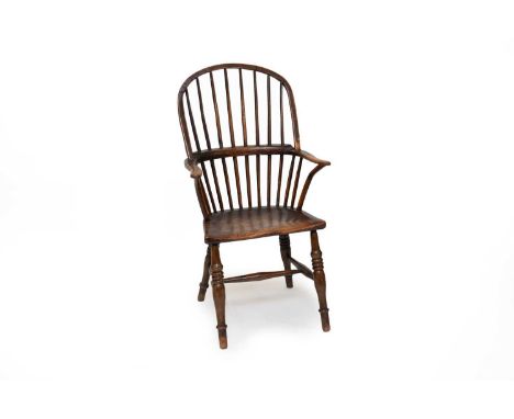 A 19th century comb-back ash Windsor chair, the hooped back with eight spindles, the saddle seat raised on ring-turned suppor