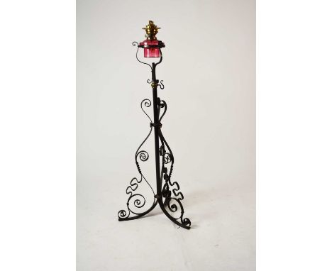 A wrought iron and cranberry glass oil lamp standard, with reservoir, the stand with tri-form scroll supports, 127cm high (la